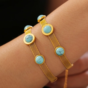 Gold mesh chain bracelet featuring turquoise round charm with roman numeral engravings