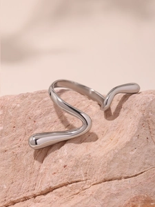 Close-up of a silver wavy open ring with a polished finish on a pink natural stone