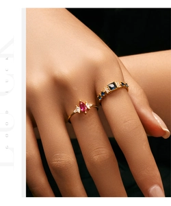 Detail of gold rings set with red marquise stone and blue gems on model hand