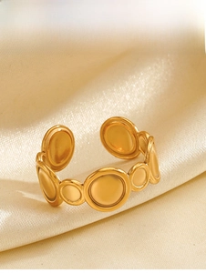 Macro detail of gold geometric ring with round discs on a champagne silk background