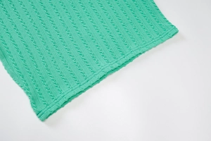 Detalle de punto verde que muestra la textura de trenzas de un vestido sin mangas
