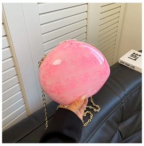 Detailed macro view of pink heart-shaped acrylic clutch with marble texture and gold chain