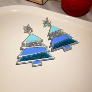Macro view of blue gradient acrylic Christmas tree earrings with glitter stars