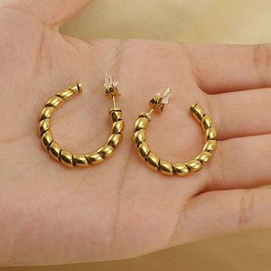 18K gold-plated stainless steel twisted hoop earrings held in hand for scale