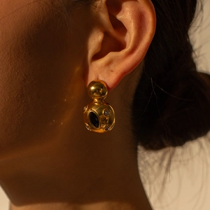 Close-up of model wearing 18k gold chunky double sphere earrings with black eye detail