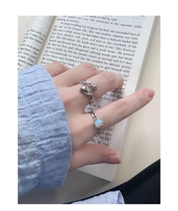 Dettaglio dell'anello in argento S925 con opale a cuore e trama a pieghe su un libro