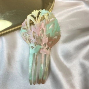 Detailed macro view of retro acetate hair comb with marble pattern on white satin