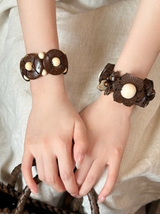 Detailed shot of handmade bohemian coconut shell and cream beaded bracelets on a linen cloth