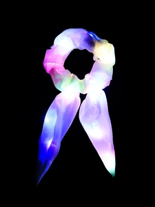 Macro shot of colorful LED lights glowing through a mesh hair scrunchie on black background