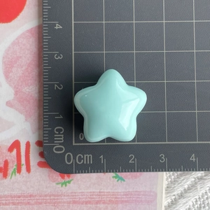 Detailed size measurement of light blue resin star charm on a centimeter cutting mat