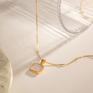 Détail du pendentif carré en nacre blanche sur une chaîne à billes plaquée or 14K