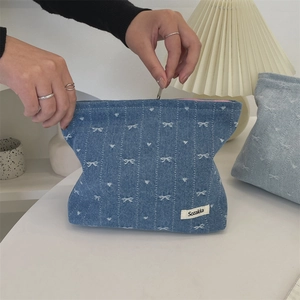 Detail of denim cosmetic bag with bow patterns and smooth zipper closure