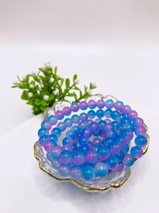 Detailed close-up of 8mm purple and blue gradient glass beads in a gold-rimmed shell dish