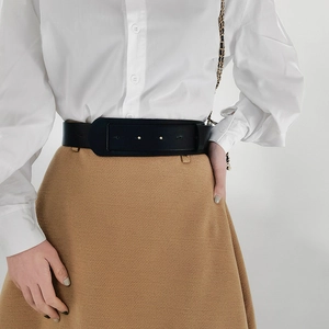 Detail of a black wide faux leather belt featuring a large square buckle and metal studs