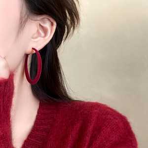 Close-up of red flocked hoop earrings on model with velvet texture and matte finish
