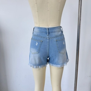 Detail of high waisted light blue denim shorts featuring frayed edges and distressed holes