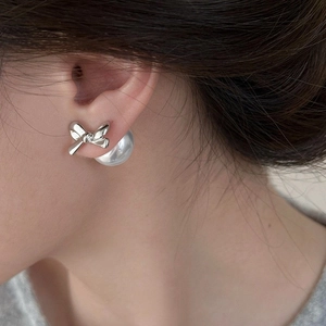 Elegante silberne Schleifen-Ohrstecker mit großen weißen Perlen-Backings am Modell