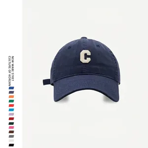 Detailed view of white letter C patch embroidery on navy blue cotton baseball cap