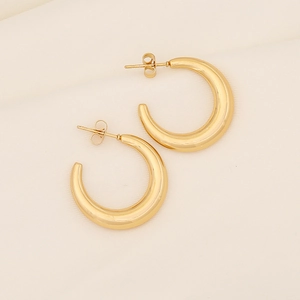 Macro view of thick C-shaped golden earrings with polished minimalist finish