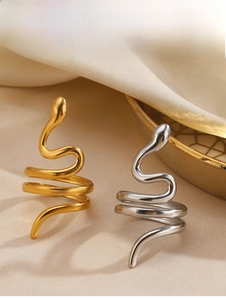 Détails de bagues en forme de serpent en finition or et argent sur fond textile chaud