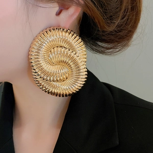 Macro shot of large golden spiral textured earrings with a high-polished metallic finish