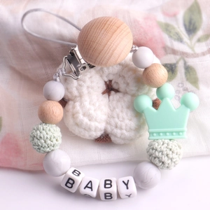 Detail of wooden pacifier clip with silicone crown bead and knitted beads for babies