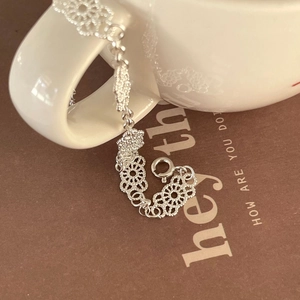 Detailed view of an S925 sterling silver lace bracelet hanging on a ceramic cup