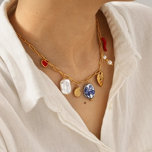 Gold stainless steel necklace featuring pearl, chili, floral and heart charms on a model