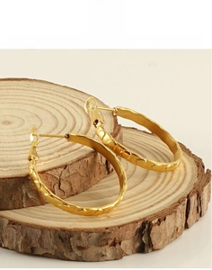 Dettaglio di orecchini a cuore in acciaio al titanio placcato oro 18k su legno