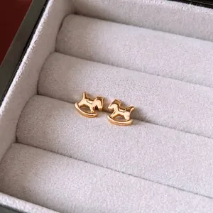 Polished 18K gold plated rocking horse stud earrings displayed in a grey velvet jewelry box