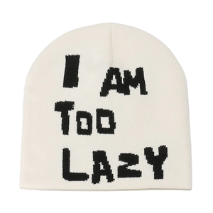 Detailed close-up of cream knit beanie with black I AM TOO LAZY jacquard lettering