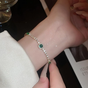 Gros plan d'un bracelet en or avec pierre verte et zircons blancs sur le poignet