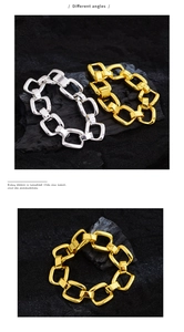 Detail of geometric chunky chain bracelets in gold and silver finish on black stone