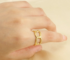 Detailed view of the 18k gold interlocking chain link ring on a soft satin fabric base