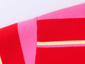 Macro view of tight stitching on colorful striped knit polo shirt with red and pink tones