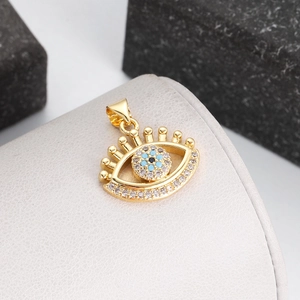 Macro shot of gold-plated evil eye pendant with blue zircon on beige leather stand