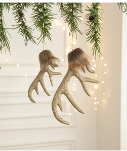 Close-up of golden glitter reindeer antler ornaments with brown faux fur on pine branch