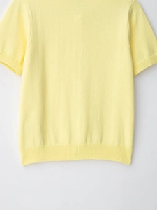 Close-up of light yellow knit top showing fine texture and ribbed edge detailing