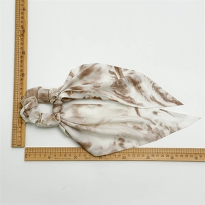 Detailed top view of white and brown marble pattern chiffon hair scrunchie with measuring ruler