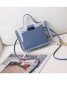 Detailed view of mini transparent PVC crossbody bag with blue leather trim on white surface