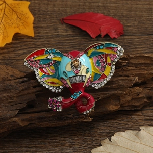 Vintage elephant brooch with colorful enamel and rhinestones on a rustic wooden base