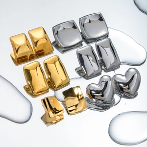 Detailed view of gold and silver geometric earrings on a reflective water drop surface