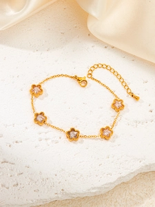Detail of adjustable gold star bracelet with clear zircons on a white stone surface