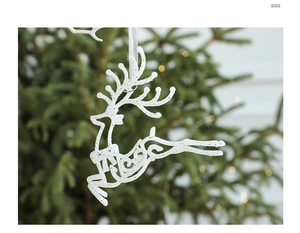 Glitzerndes weißes Rentier-Ornament am Weihnachtsbaum mit unscharfen grünen Nadeln