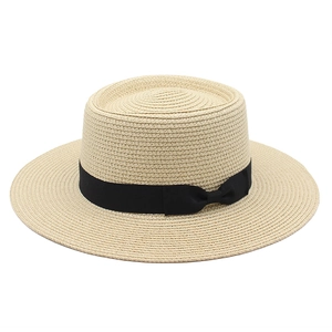 Close-up of a wide-brim boater hat featuring fine straw weaving and a black ribbon bow