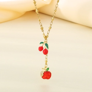 Detailed view of red enamel cherry and apple charms with zircon accents on a gold necklace