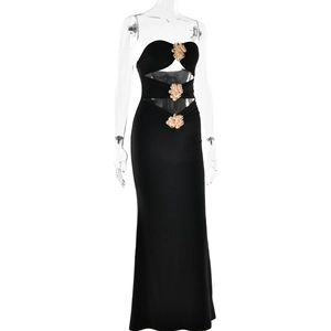 Detalle de vestido largo negro con aberturas y adornos de flores doradas en la cintura
