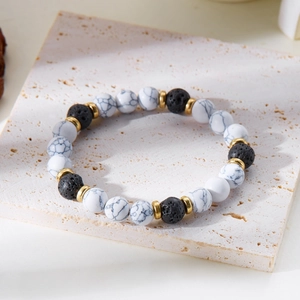 Close-up of 8mm natural white marble and black lava stone beads with gold spacers
