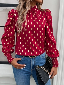 Detailed view of women's red long sleeve blouse with gold polka dots and puff sleeves