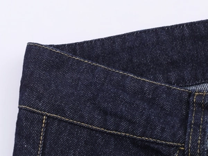 Détail du denim bleu foncé avec coutures contrastées au gingembre sur la ceinture